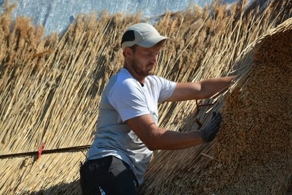 en mand ved siden af et bjerg af halm